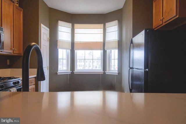 kitchen with light countertops, brown cabinets, and freestanding refrigerator