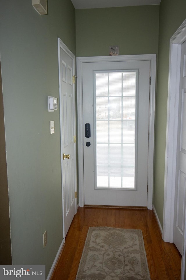 doorway to outside featuring baseboards and wood finished floors