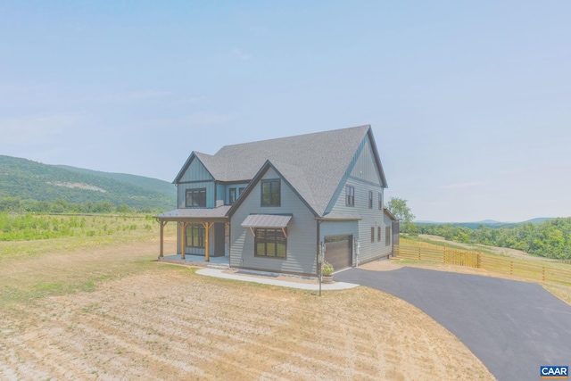 view of front of house featuring an attached garage, board and batten siding, fence, driveway, and a mountain view