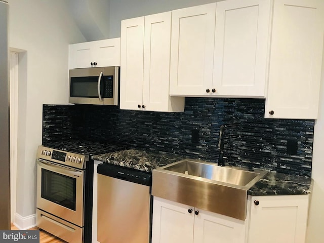 kitchen with a sink, white cabinets, tasteful backsplash, and stainless steel appliances