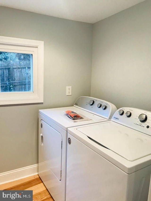 washroom featuring washing machine and clothes dryer, laundry area, light wood finished floors, and baseboards