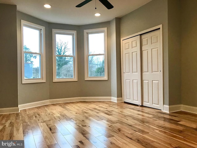 unfurnished bedroom with baseboards, multiple windows, and wood finished floors