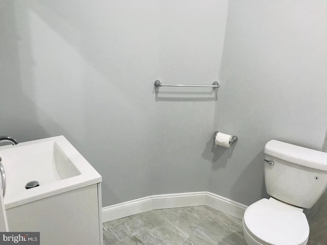 bathroom with toilet, vanity, and baseboards