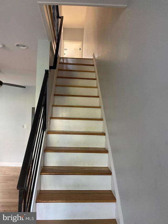 staircase featuring ceiling fan, baseboards, and wood finished floors