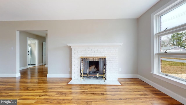 unfurnished living room featuring baseboards, wood finished floors, and a fireplace