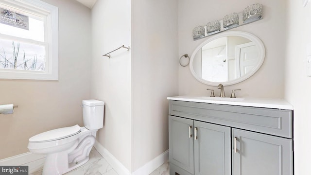 bathroom with marble finish floor, toilet, vanity, and baseboards