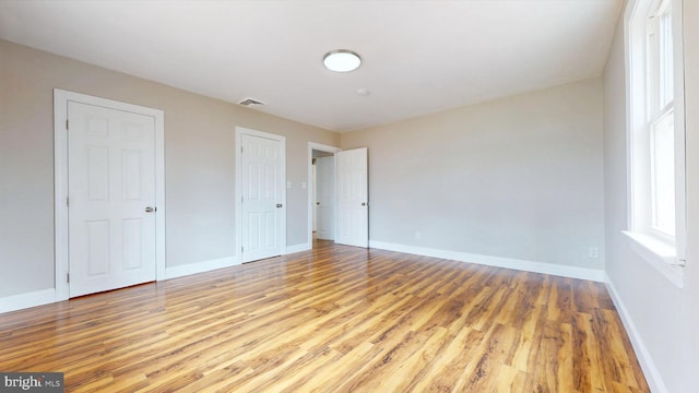 unfurnished bedroom with visible vents, light wood-type flooring, and baseboards