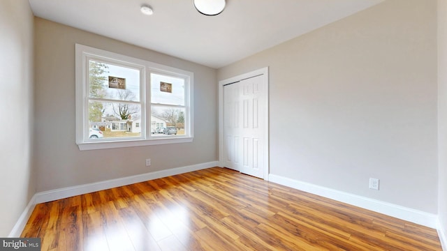 unfurnished bedroom with light wood finished floors, a closet, and baseboards