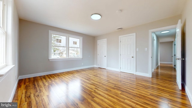 unfurnished bedroom with visible vents, baseboards, and wood finished floors