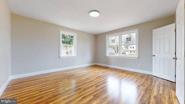 spare room with baseboards and wood finished floors