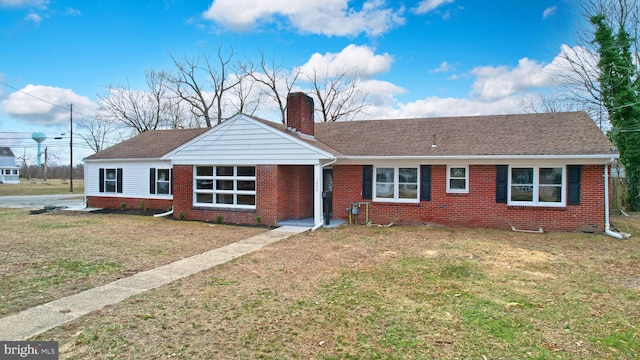 ranch-style home with a shingled roof, a front yard, brick siding, and a chimney