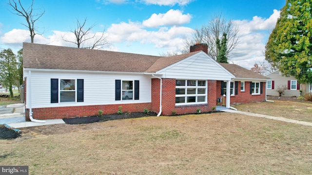 ranch-style house featuring a front yard, brick siding, and a chimney