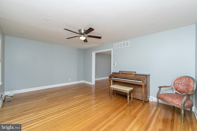 living area with light wood-style flooring, a ceiling fan, visible vents, and baseboards