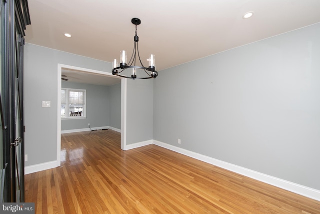 unfurnished room featuring recessed lighting, baseboards, an inviting chandelier, and light wood finished floors