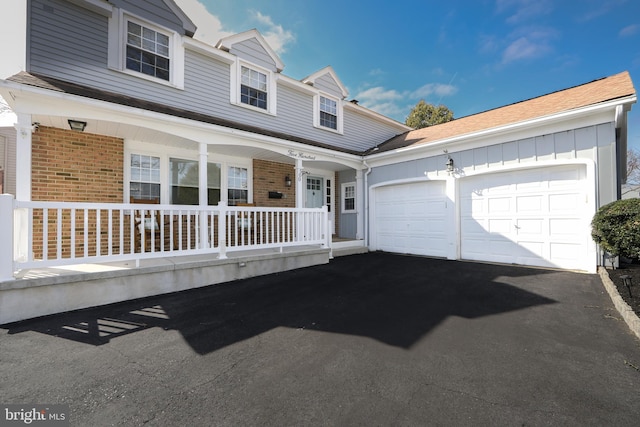 view of front of house with a garage, brick siding, a porch, and aphalt driveway