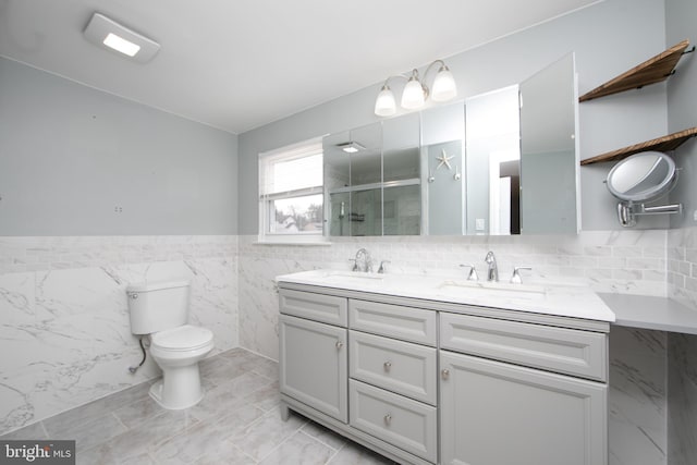 full bathroom with a sink, toilet, a stall shower, and double vanity