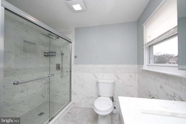 bathroom featuring a wainscoted wall, toilet, a marble finish shower, tile walls, and vanity