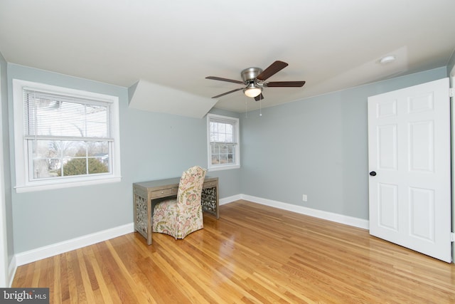 living area with baseboards, light wood-type flooring, and ceiling fan