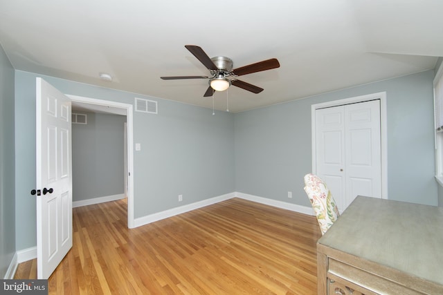 unfurnished office with light wood-style flooring, a ceiling fan, visible vents, and baseboards