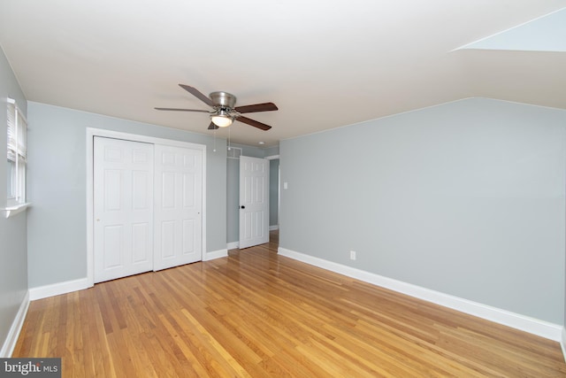 unfurnished bedroom featuring a closet, baseboards, light wood-style flooring, and a ceiling fan