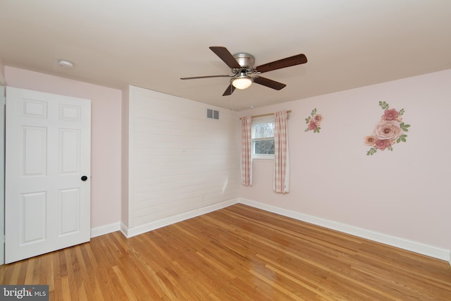 spare room featuring light wood finished floors, visible vents, baseboards, and a ceiling fan