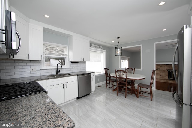 kitchen featuring a sink, dark stone counters, appliances with stainless steel finishes, and white cabinetry