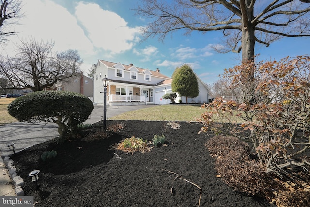 rear view of house featuring driveway, a yard, covered porch, and an attached garage