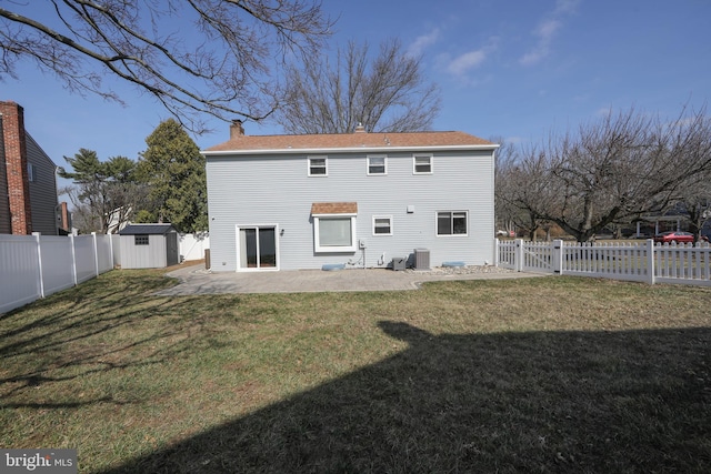 rear view of house featuring a storage shed, a fenced backyard, a chimney, and a patio area