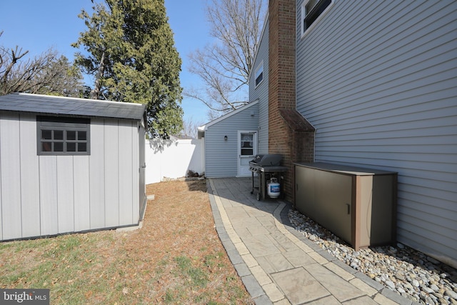 view of side of home with a storage unit, an outbuilding, a patio area, and fence