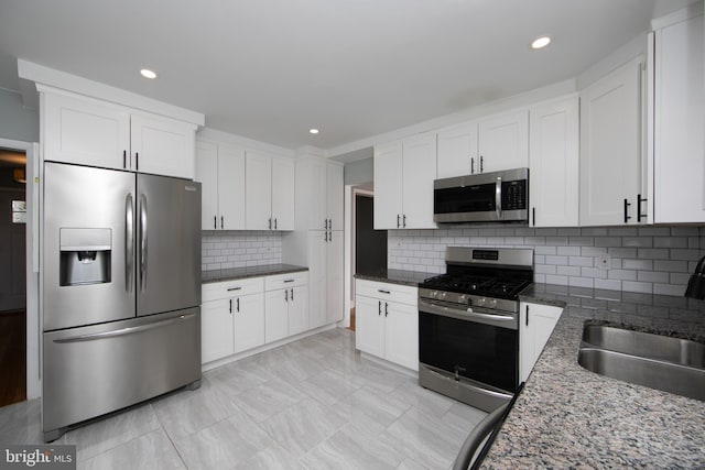 kitchen featuring a sink, backsplash, appliances with stainless steel finishes, and white cabinets