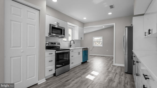 kitchen with visible vents, backsplash, appliances with stainless steel finishes, white cabinets, and light wood finished floors