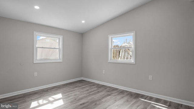 spare room with lofted ceiling, recessed lighting, wood finished floors, and baseboards