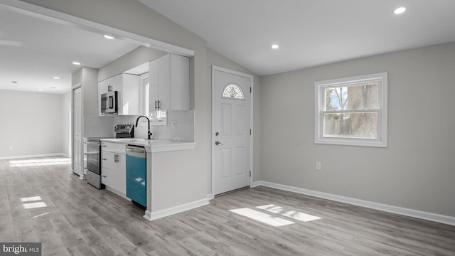 kitchen featuring backsplash, light wood-type flooring, light countertops, white cabinets, and stainless steel appliances