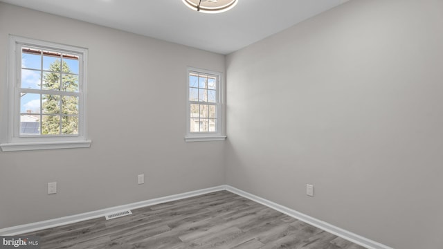 spare room with visible vents, baseboards, and wood finished floors