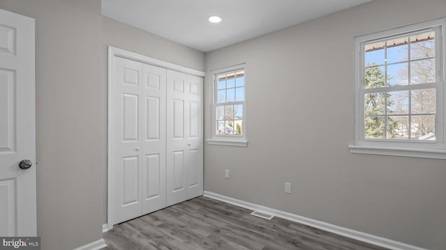 unfurnished bedroom featuring visible vents, baseboards, recessed lighting, wood finished floors, and a closet