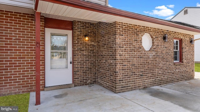 property entrance featuring a patio area and brick siding