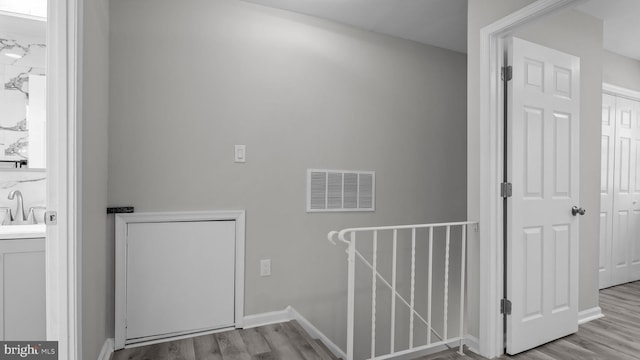 interior space with visible vents, a sink, baseboards, and wood finished floors