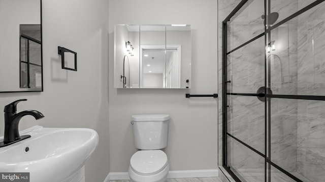 full bath featuring toilet, marble finish floor, a sink, a shower stall, and baseboards