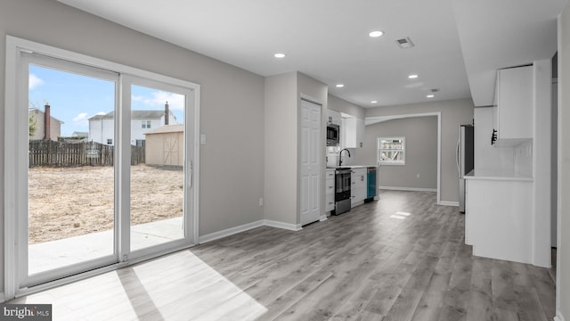 unfurnished living room featuring plenty of natural light, light wood-style floors, recessed lighting, and baseboards