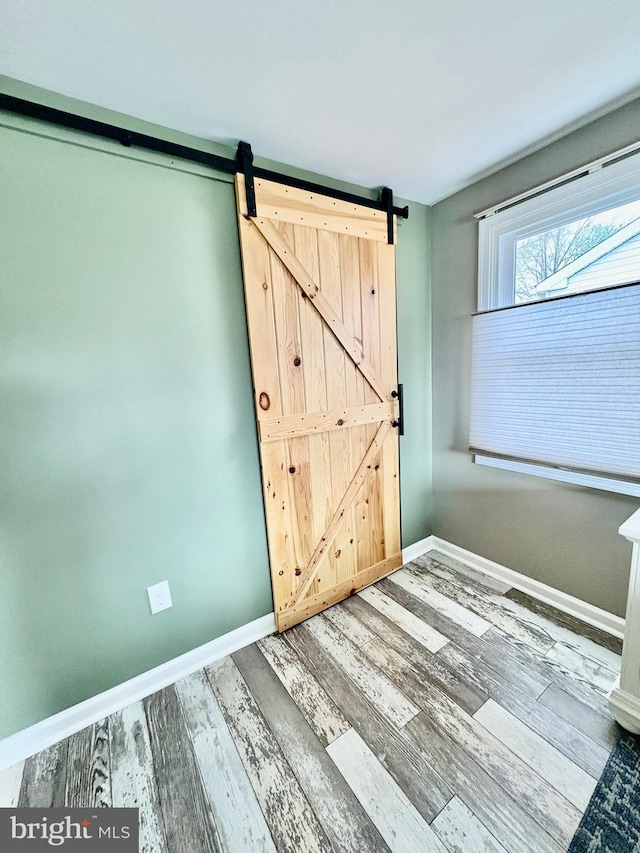 interior space featuring a barn door, baseboards, and wood finished floors