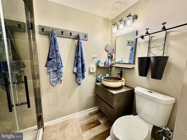 full bathroom featuring a stall shower, toilet, vanity, and baseboards