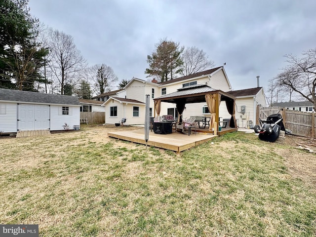 rear view of property featuring an outbuilding, a shed, a gazebo, a yard, and fence