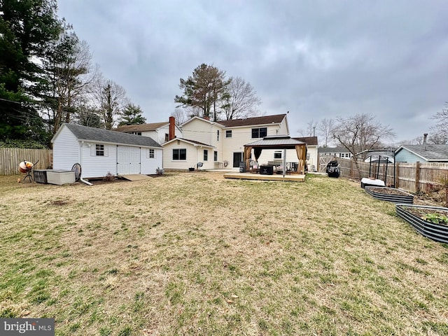 rear view of house featuring a gazebo, a lawn, and fence