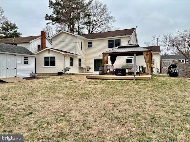 back of house featuring a gazebo, fence, a lawn, and an outbuilding