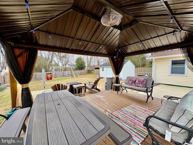 wooden terrace with a fenced backyard, a gazebo, an outdoor structure, a storage unit, and a lawn