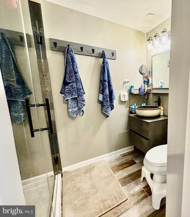 bathroom with vanity, wood finished floors, baseboards, a stall shower, and toilet