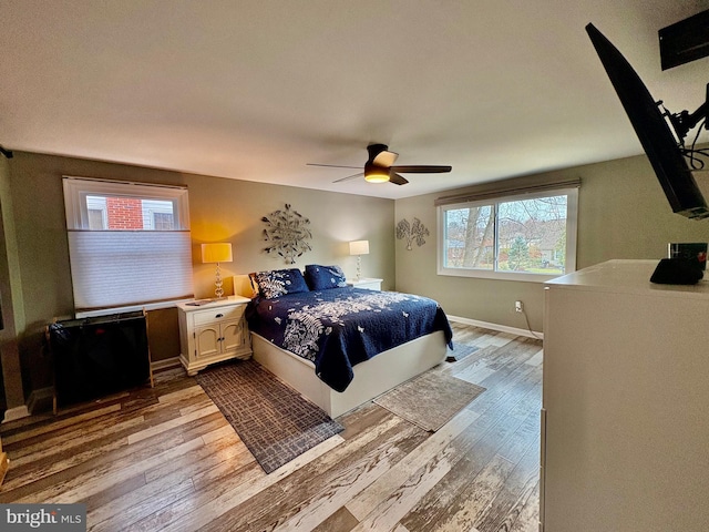 bedroom with a ceiling fan, wood finished floors, and baseboards