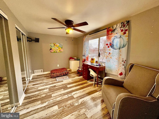 sitting room featuring ceiling fan, visible vents, baseboards, and wood finished floors