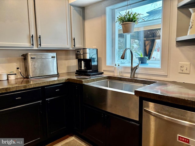 kitchen with stainless steel dishwasher, dark countertops, dark cabinets, and a sink