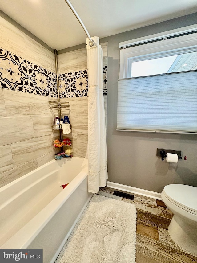 bathroom featuring wood finished floors, baseboards, visible vents, shower / bath combination with curtain, and toilet